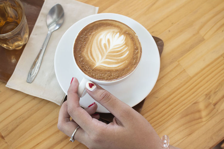 Cropped hands of cappuccino on table