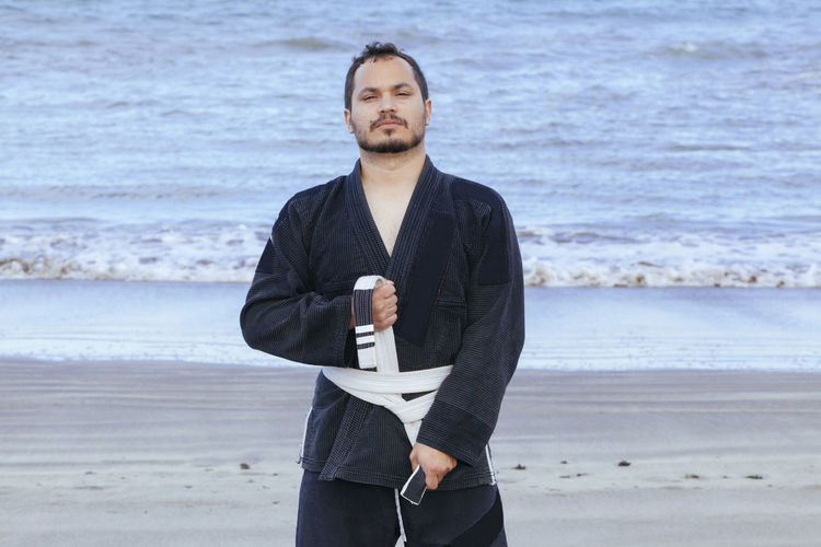 Portrait of man wearing uniform while standing at beach