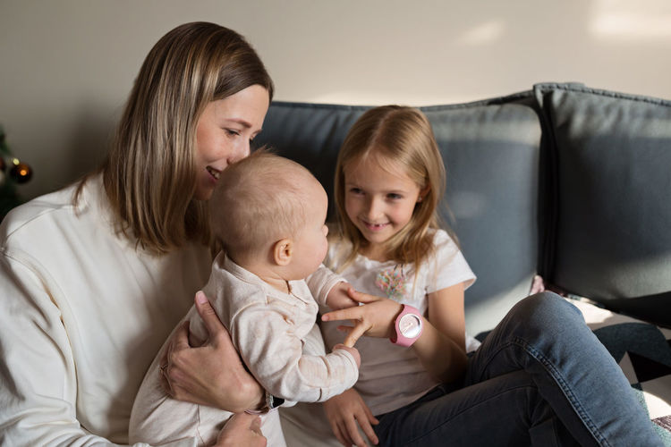 Mother and daughter playing while sitting on sofa at home