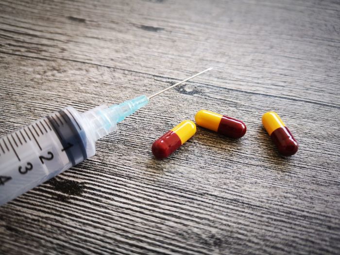 Close-up of syringe and pills on table