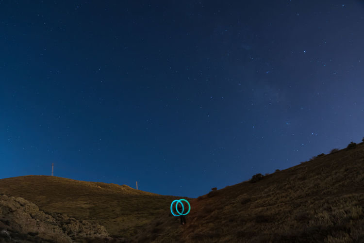 Low angle view of person with light painting on mountain at night