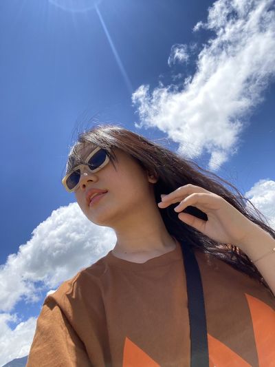Low angle view of woman wearing sunglasses against sky