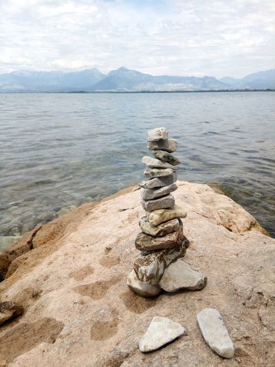 Stack of stones by sea against sky