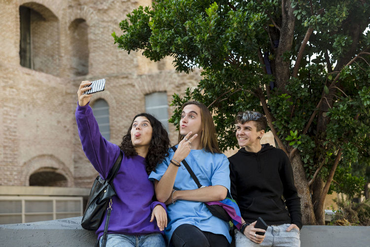 Young diverse friends taking selfie with a mobile phone outdoors.