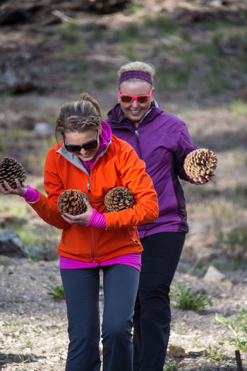 Smiling women holding pine cone outdoors