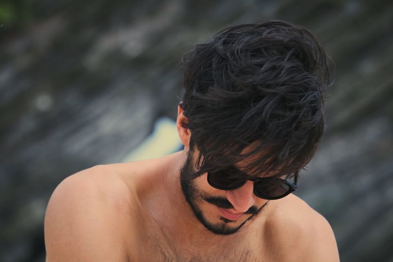 Close-up of shirtless man wearing sunglasses looking down