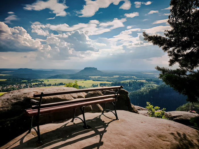 View of park bench by mountains against sky