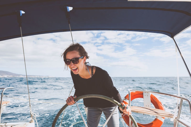 Smiling young woman steering boat on sea