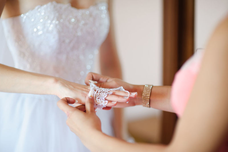 Midsection of woman putting lace on bride