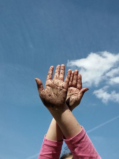 Low angle view of dirty hands against sky