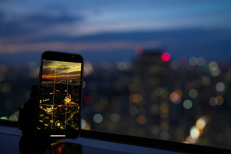 Close-up of illuminated smart phone against sky during sunset