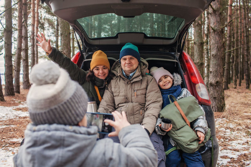 Winter family road trip. happy parents with kids make photo in the trunk of car during walking