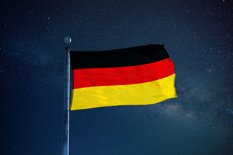 Low angle view of german flag against star field sky