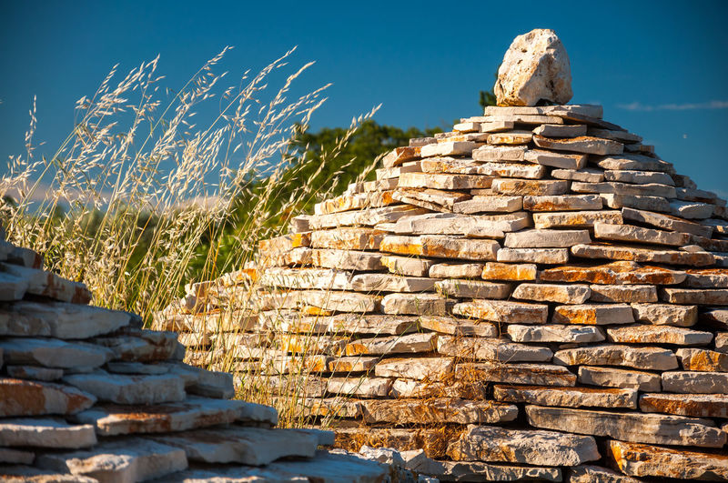 Stack of rocks on stone wall against sky