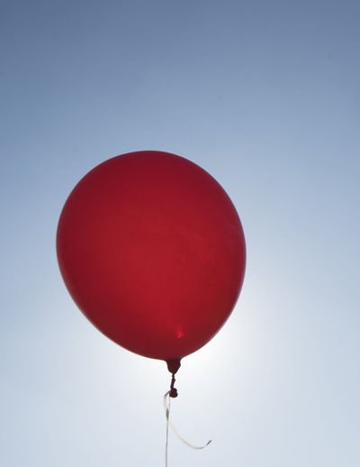 Low angle view of red balloon against blue sky
