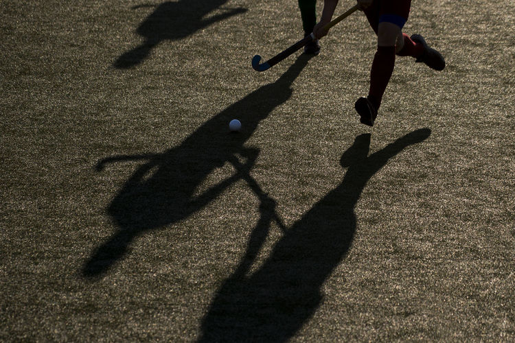 Low section of players playing hockey on field