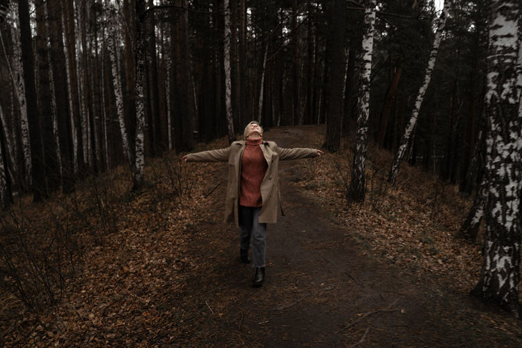Young woman standing amidst trees in forest