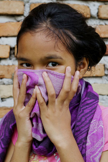 Close-up portrait of girl covering face with scarf