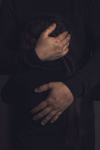 Close-up of man holding hands over black background