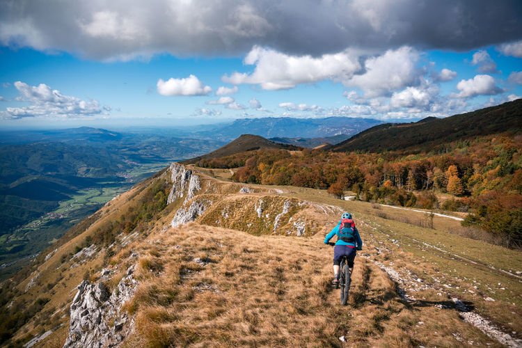 Woman mountain biking on footpath near ridge on mount nanos above vipava, slovenia.