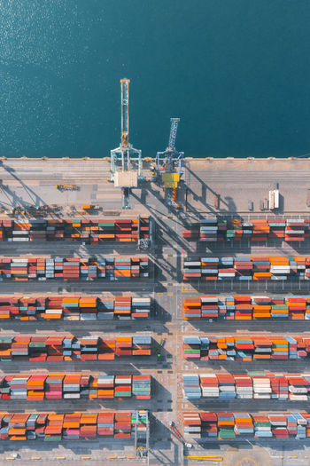 Full frame of drone view of multicolored cargo containers arranged in parallel lines on ship dock