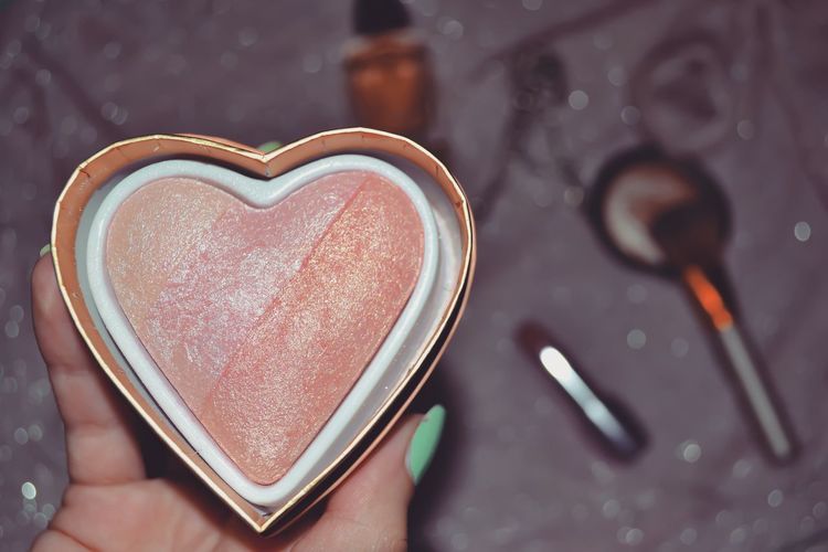 Cropped woman hand holding heart shaped blusher