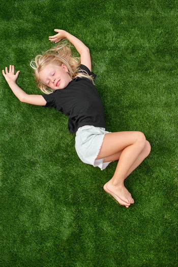 Full length of young woman lying on grassy field