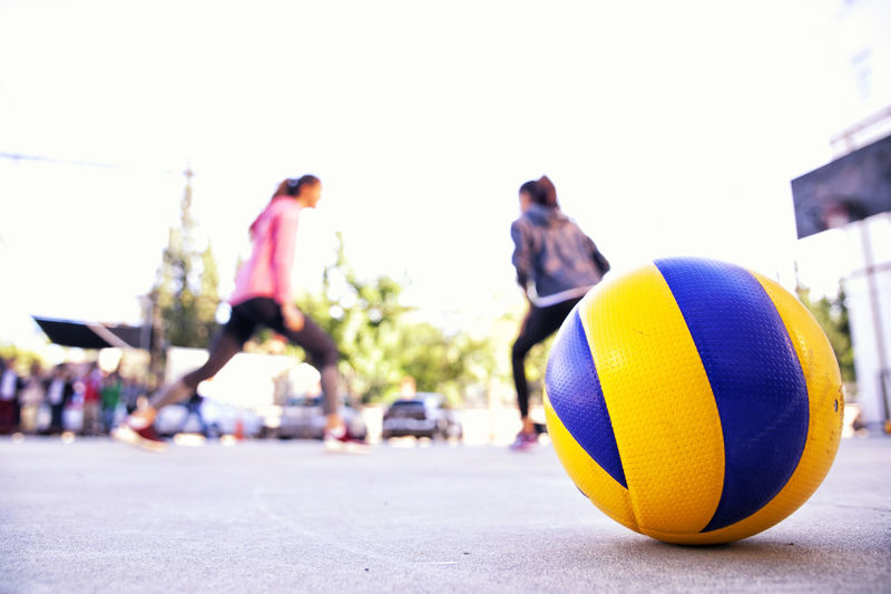 Close-up of ball with women playing against sky