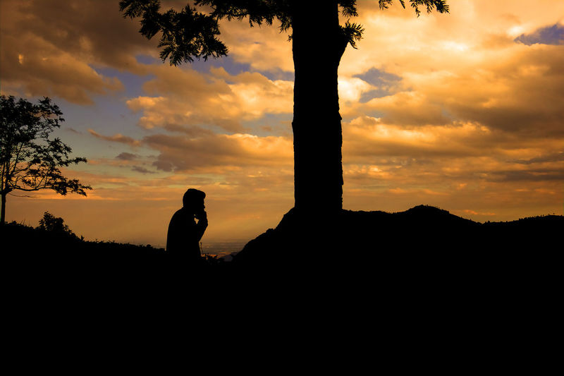 Silhouette man standing against dramatic sky during sunset