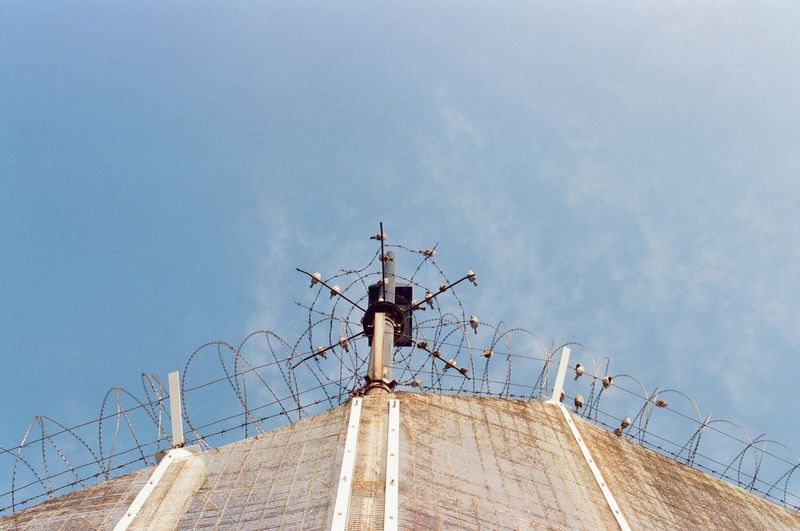 Low angle view of cross on building against sky