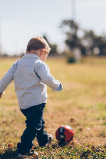 Full length of boy playing with ball on field