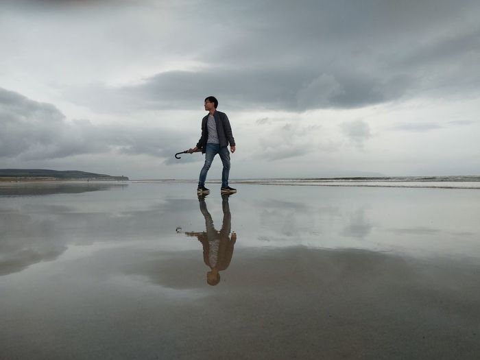Full length of man standing at beach against sky