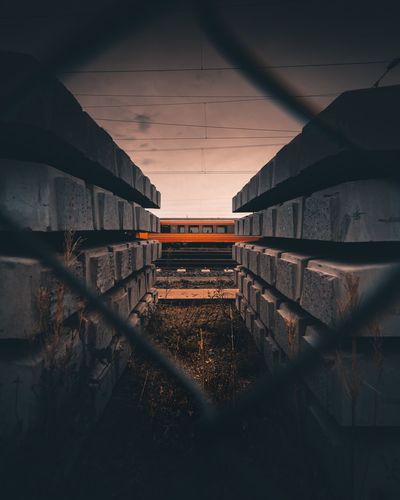 Train on railroad track seen through fence during sunset