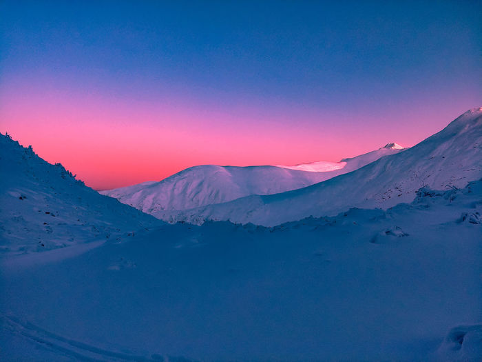 Scenic view of snowcapped mountains against sky during red sunset