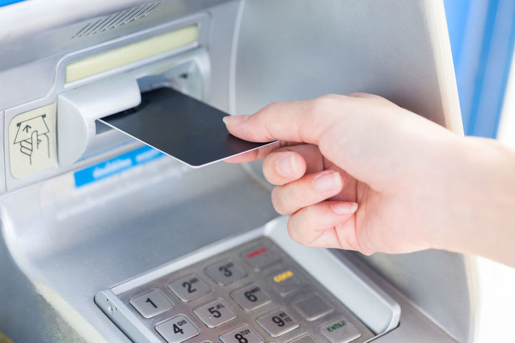 Cropped hand of woman using atm