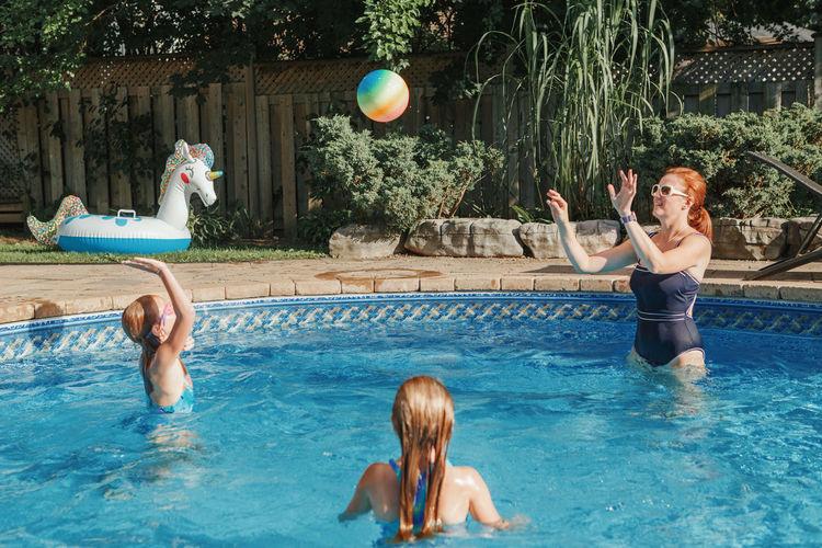 Mother playing ball with daughters children in swimming pool. family having fun in swimming pool 