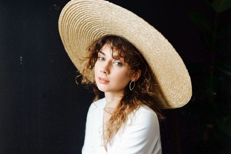 Portrait of young woman wearing hat with curly hair 
