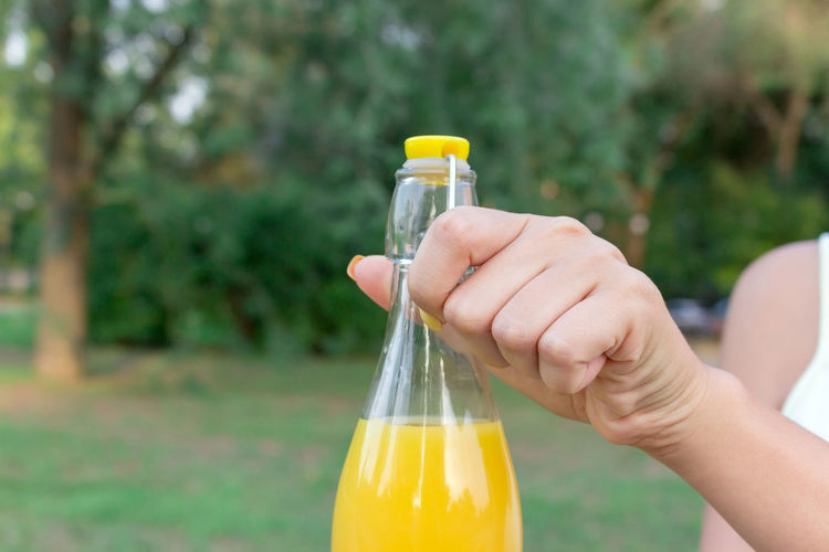 Close-up of hand holding glass bottle against blurred background