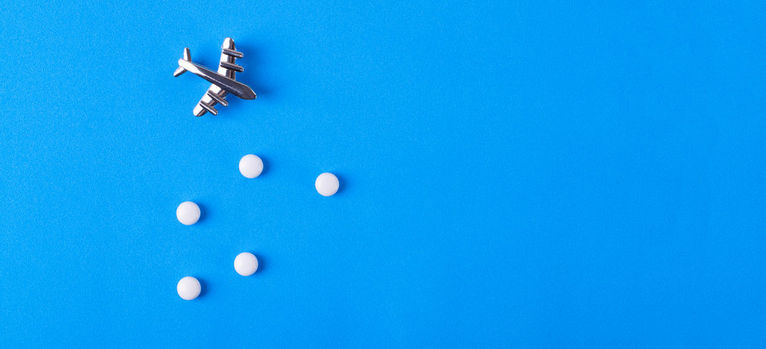 Directly above shot of airplane with pills over blue background