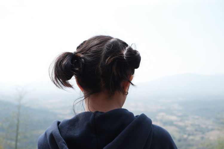 Rear view of woman looking at mountain against sky