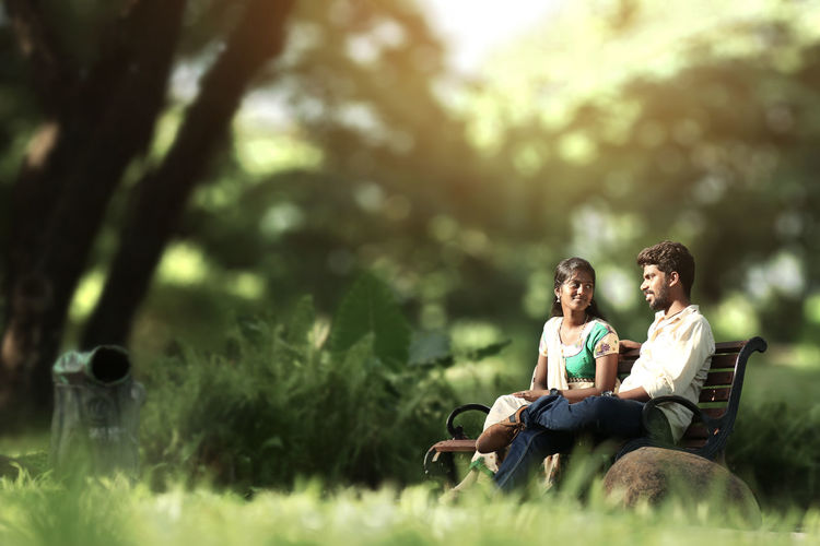 Tilt-shift image of man and woman sitting on bench at park