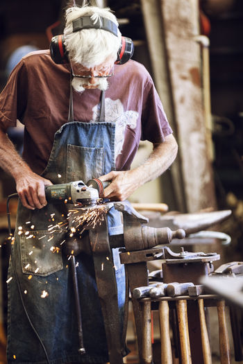 Senior man working with grinder at workshop