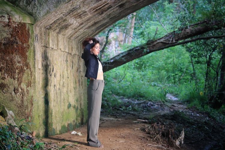 Woman standing under bridge in forest