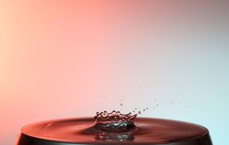 Close-up of water crown in glass against colored background
