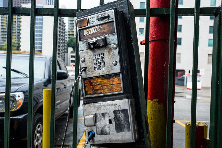Abandoned pay phone by railing in city