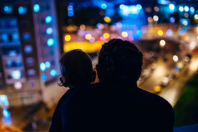Rear view of silhouette mother with son in illuminated city at night