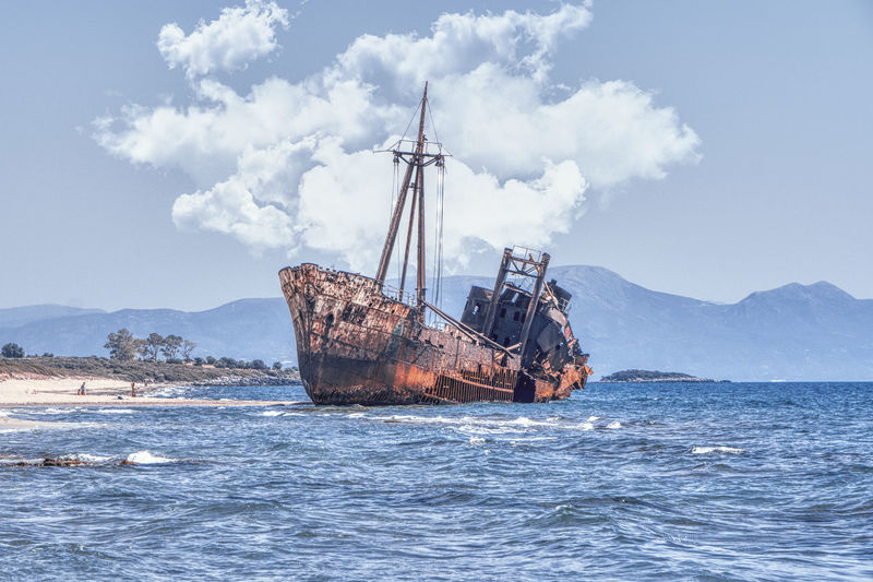 Shipwreck at beach on sea against sky