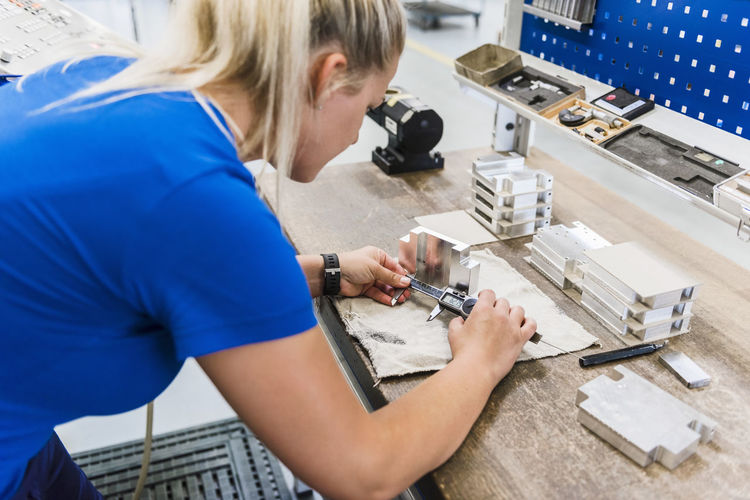 Woman measuring metal workpiece
