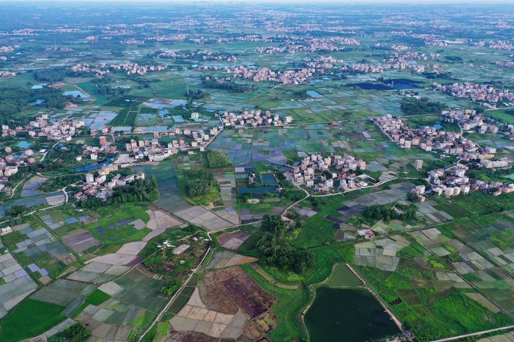 Aerial view of agricultural field by buildings in city