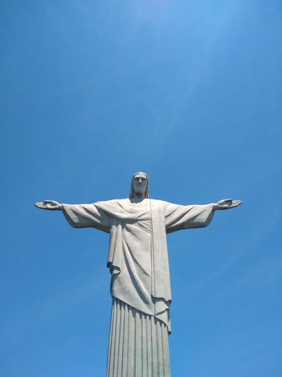 Low angle view of jesus statue against blue sky